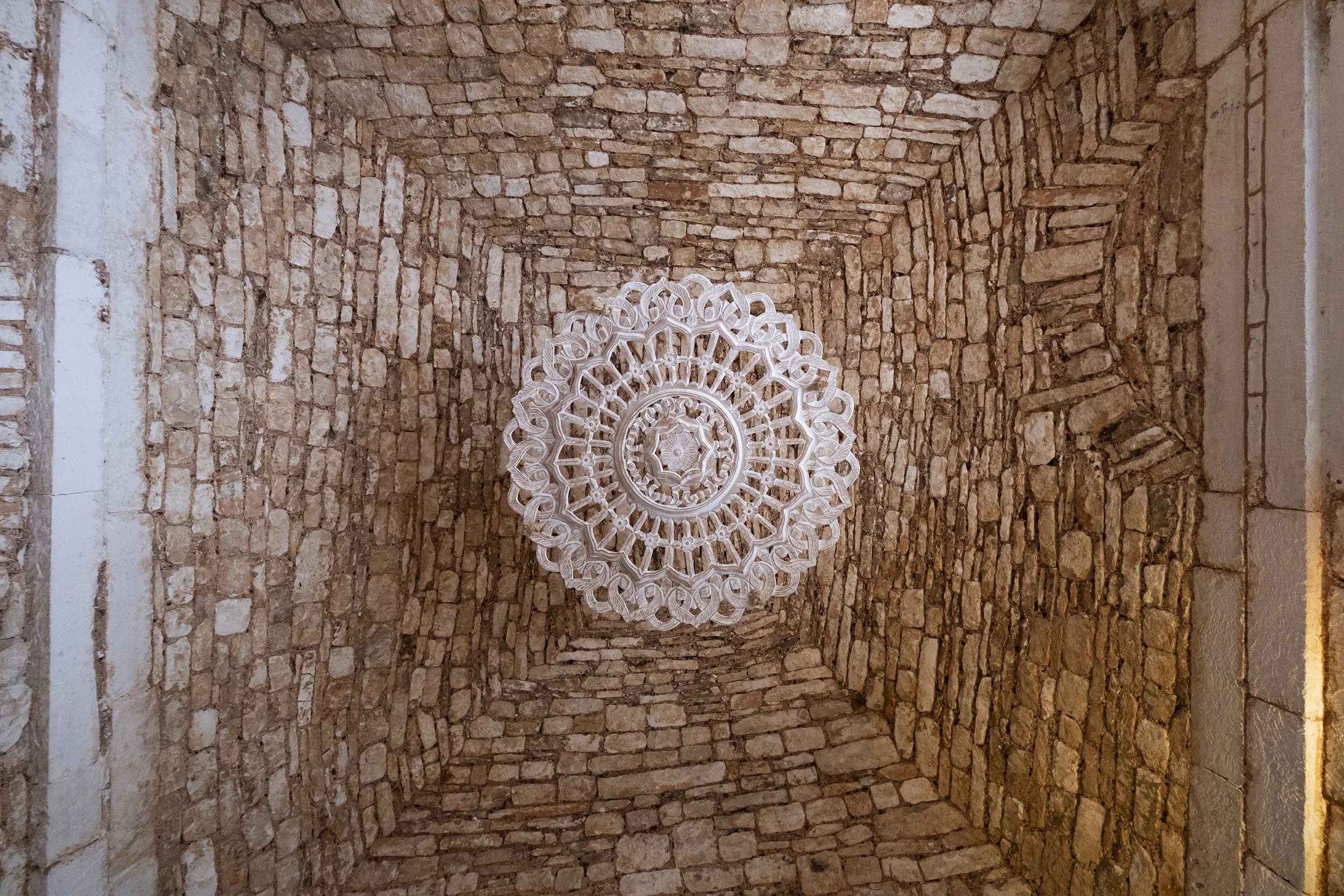A brick ceiling with an intricate white chandelier hanging from the center.