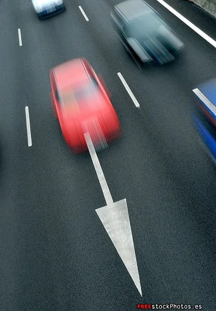 Blurred red and blue cars moving on a highway with lane markings