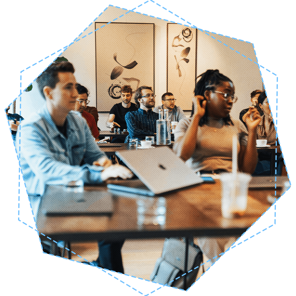 group of diverse individuals sitting at tables wit laptoons