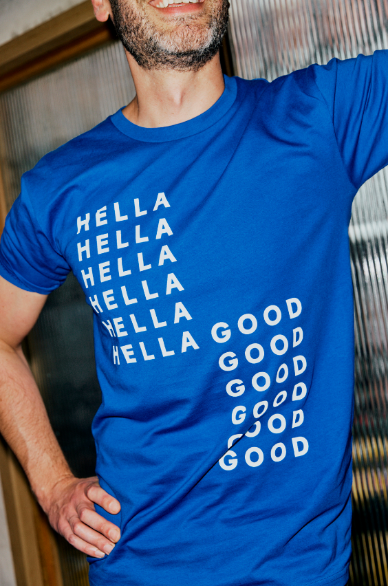 A man wearing a blue T-shirt with the words 'HELLO' repeated five times and 'GOOD' repeated six times in a diagonal pattern