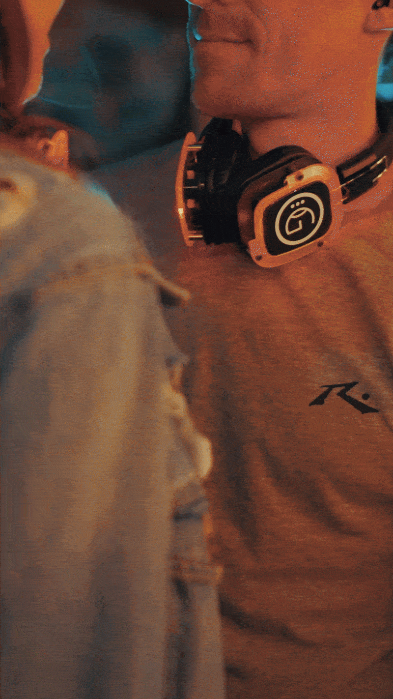 A person wearing headphones kisses a dog.