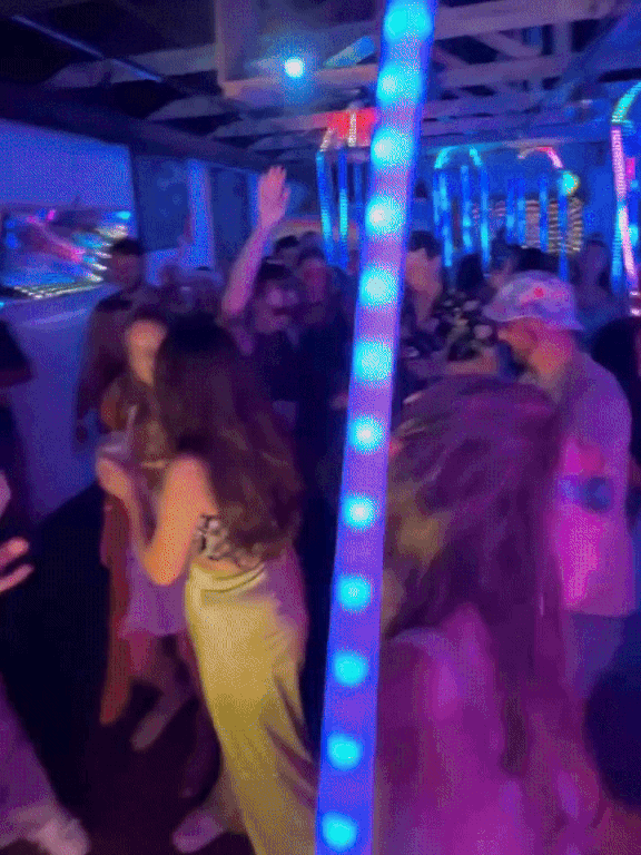 People dancing and socializing at a nightclub with colorful LED lights and a lively atmosphere.