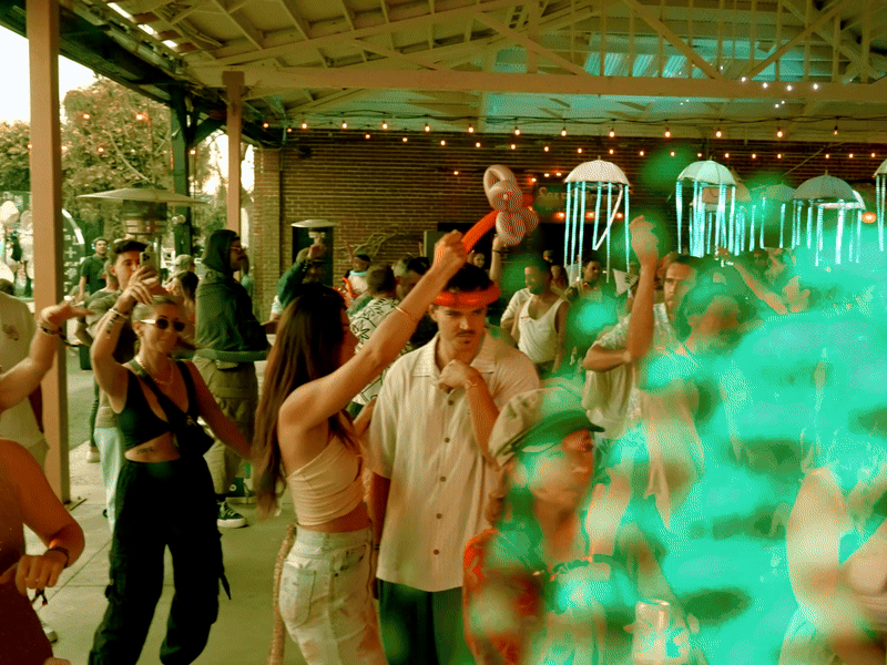 People dancing and enjoying a party with colorful lights at an outdoor venue.