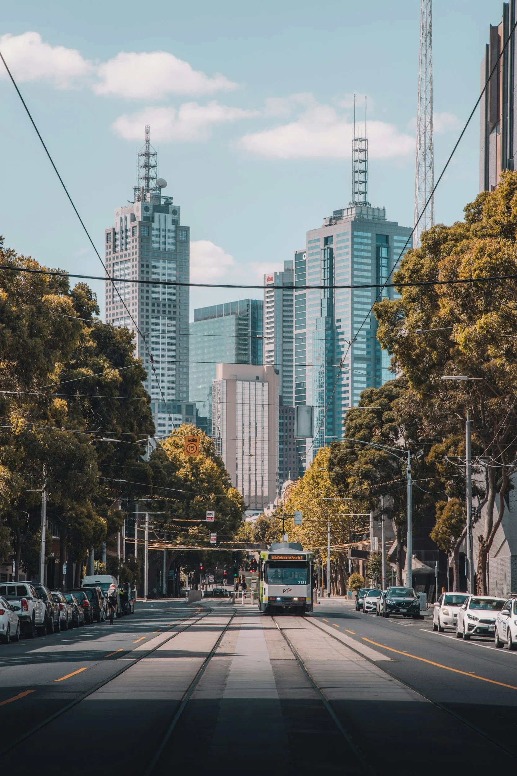 A Melbourne street with a tram and office towers in the background