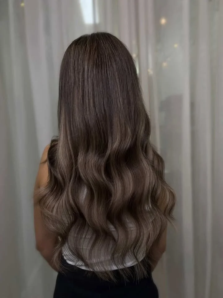 Back view of a woman with long, wavy, shiny brown hair