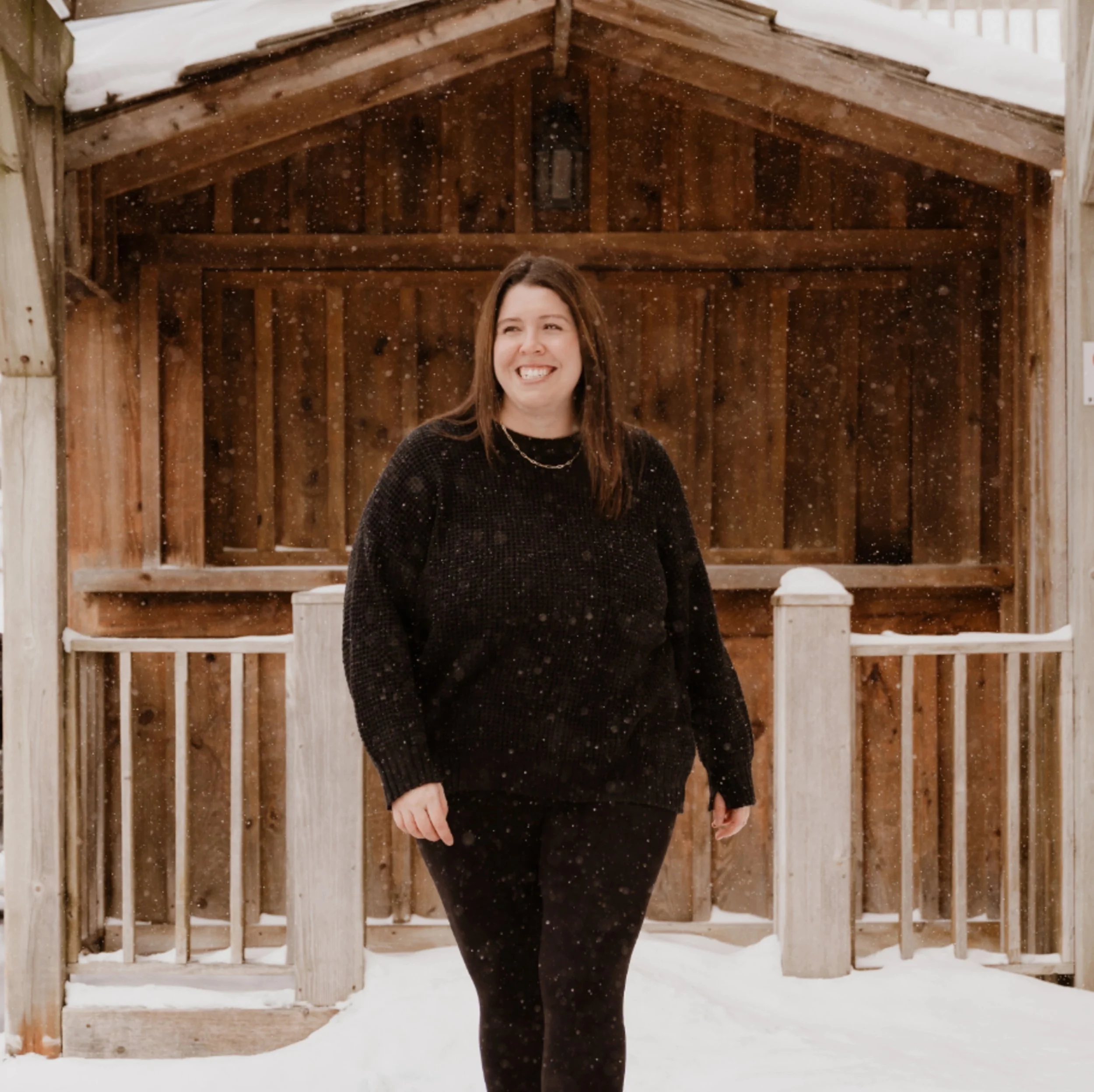 Amanda of Her Truth standing in snow flurries and smiling at the camera
