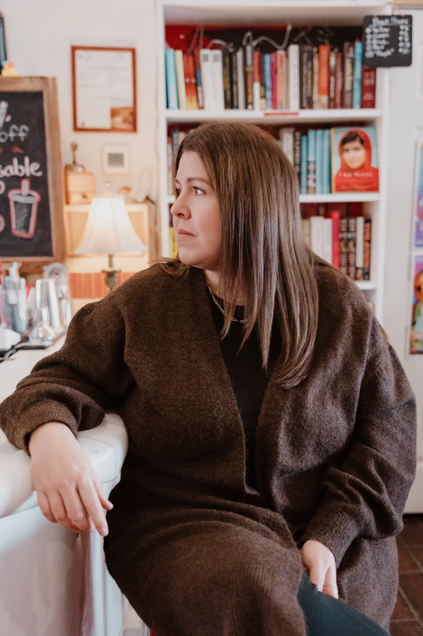 Amanda of Her Truth sitting at a bookstore coffee shop, looking to her left.