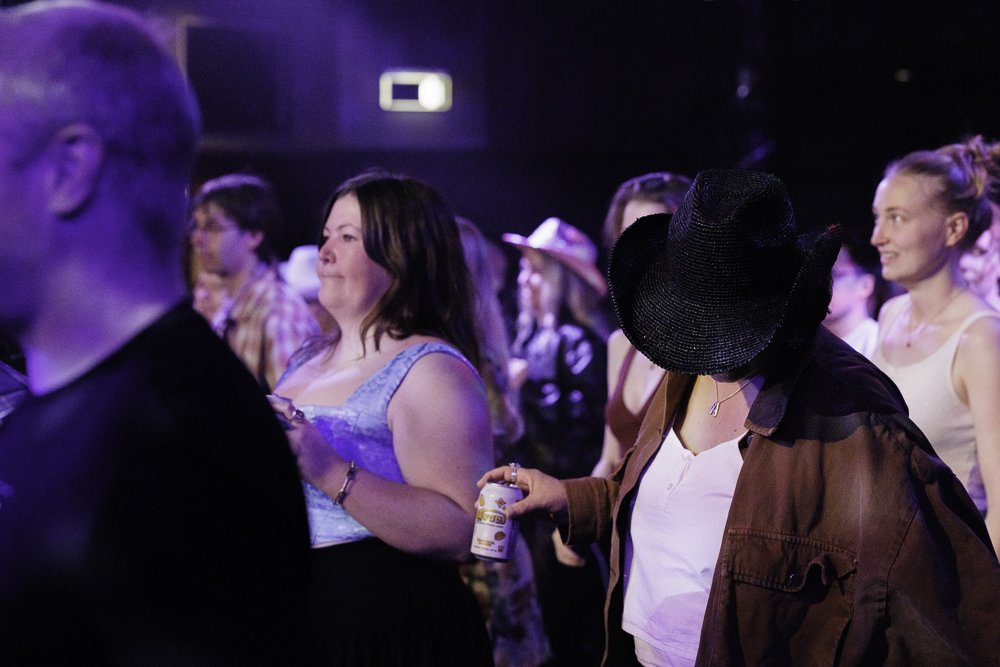 People dancing and enjoying music at a party or concert, some with hats and casual clothing.