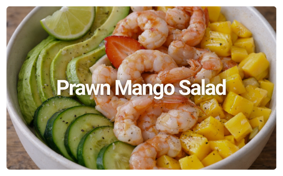 A bowl containing a shrimp, mango, cucumber, and avocado salad with lime wedges.