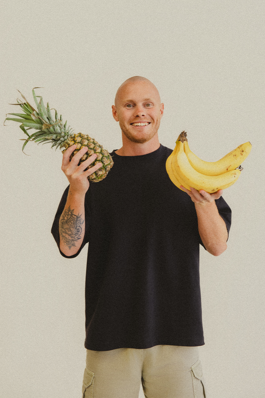 Lachy Oliver wearing a black shirt holding a pineapple and bananas smiling