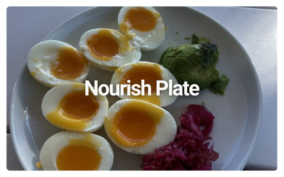 A white plate with six halved soft-boiled eggs, an avocado, and some shredded red cabbage.