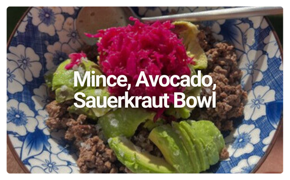 A bowl containing minced meat, avocado slices, and pickled cabbage, served in a blue and white patterned bowl.