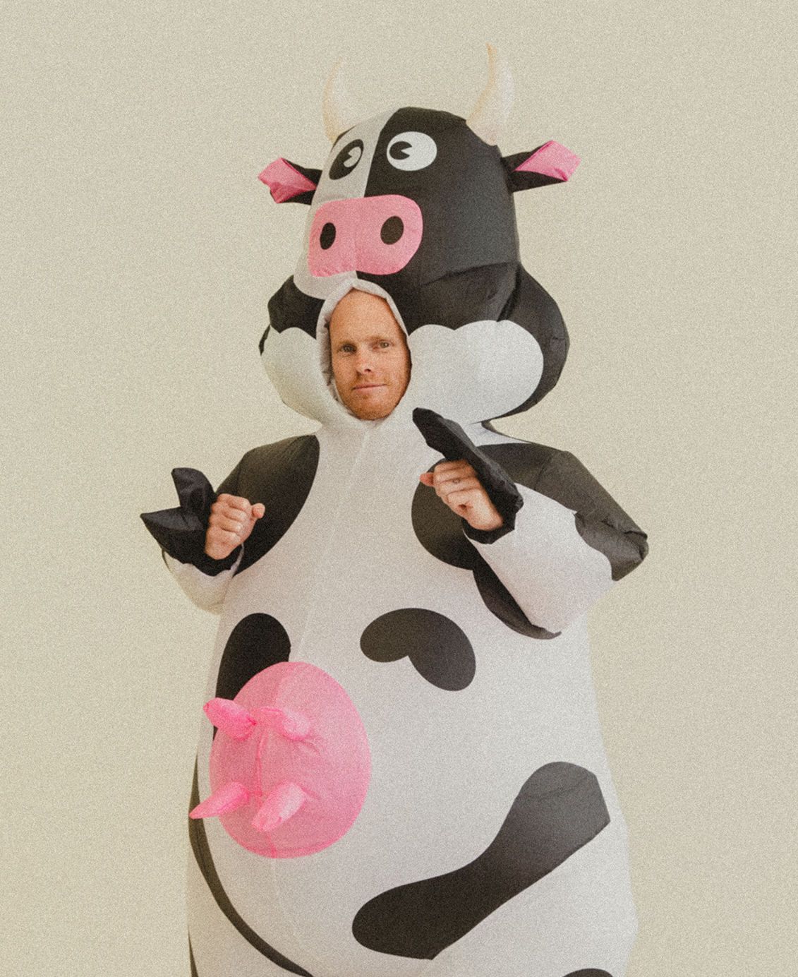 Lachy Oliver wearing a cow costume with his hands up in fists looking seriously at the camera