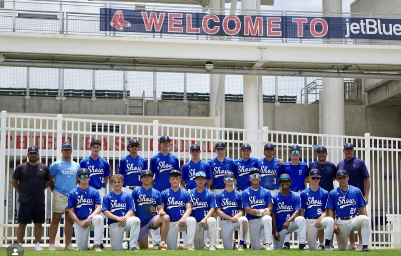 Showtime Select 16U posing for a photo in front of a white fence at a JetBlue Park under a bridge with a welcome banner during the Perfect Game BCS National Championship