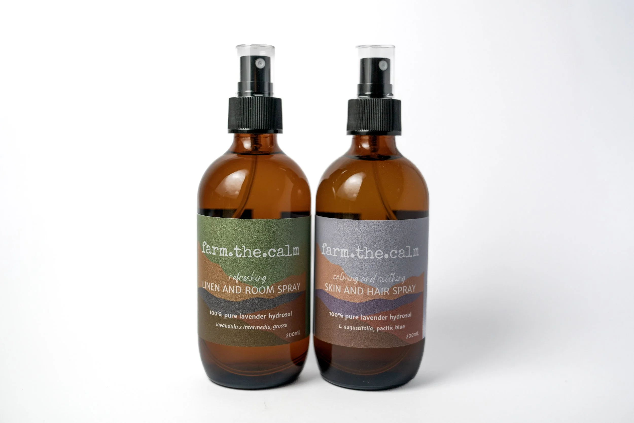 Two brown glass spray bottles with black spray caps, labeled 'farm.the.calm' for linen and room spray and skin and hair spray, on a plain white background.