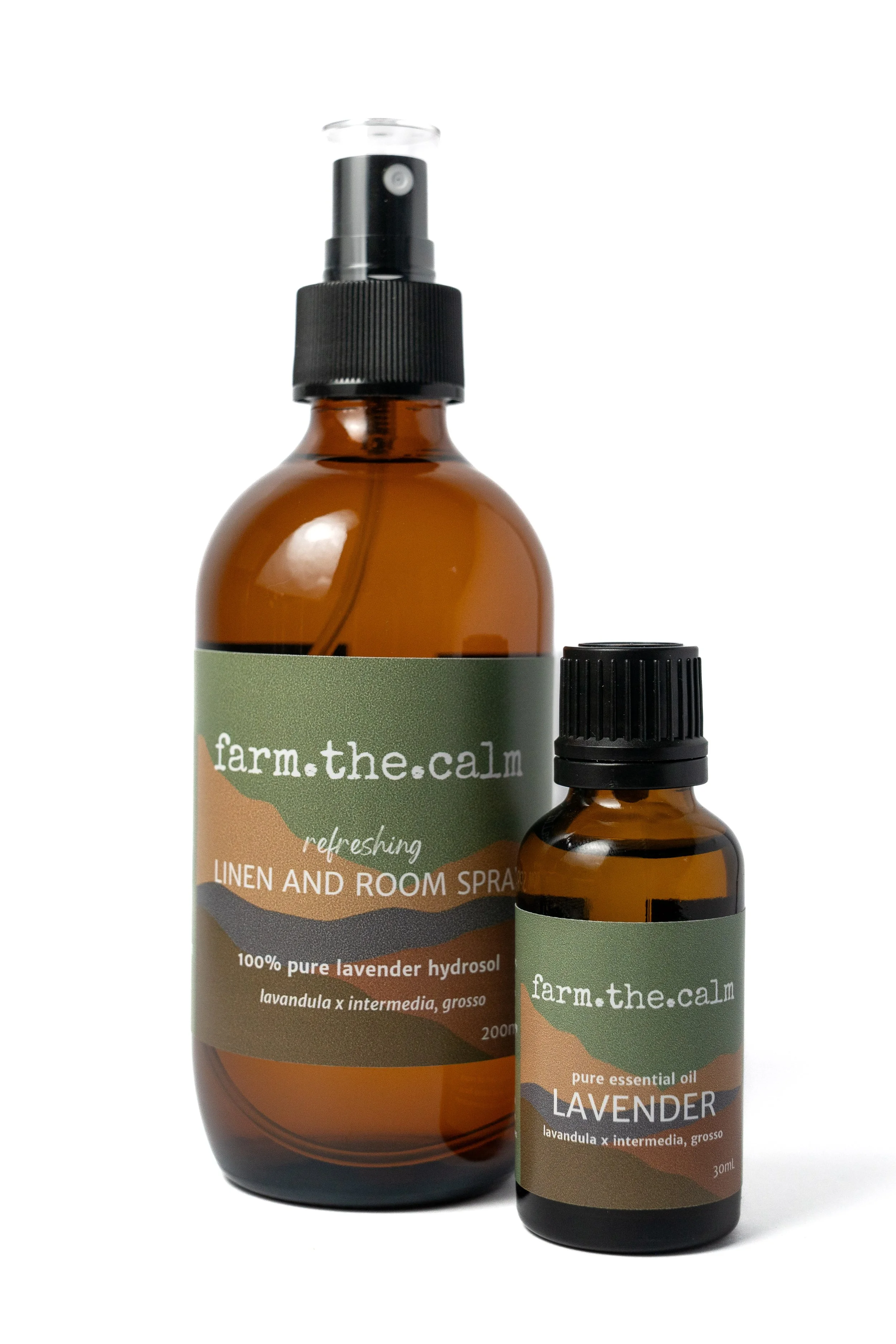 Two amber bottles of lavender products, one with a spray nozzle labeled 'farm.the.calm refreshing linen and room spray, 100% pure lavender hydrosol, 200ml' and the other with a black cap labeled 'farm.the.calm pure essential oil, lavender, 30ml'.