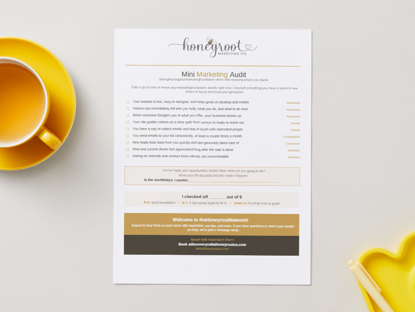 Marketing audit checklist from Honeyroot Marketing Co. on a desk with a yellow mug and yellow heart-shaped dish.