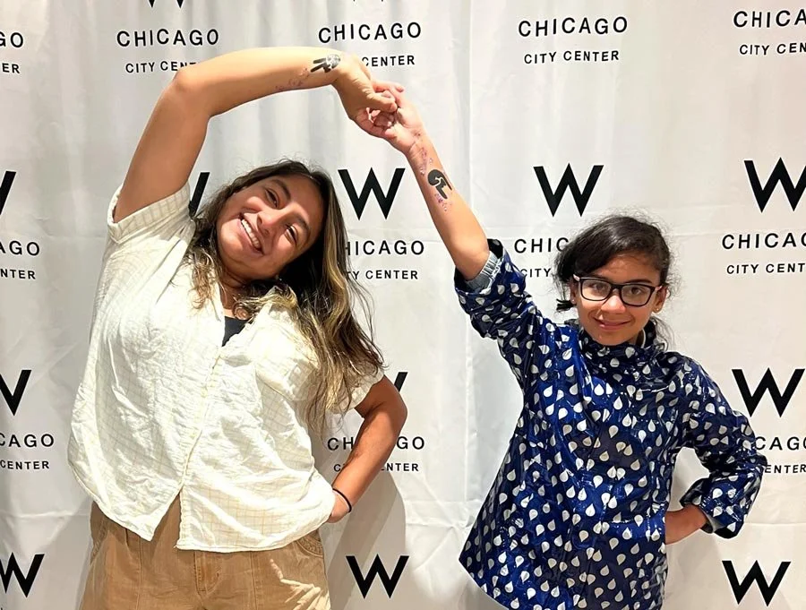 Mother and daughter poses with their hands joined and shows off their tattoos on their wrist and forearm.