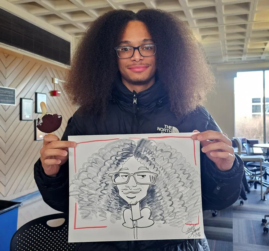 A man with thick, curly hair is holding up his caricature.