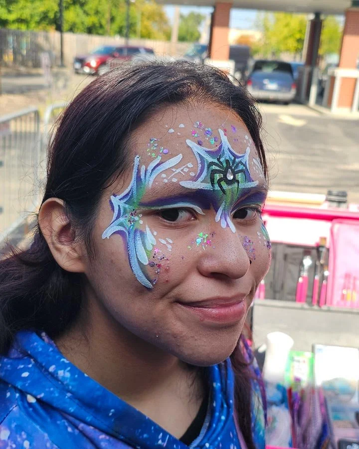 A teenager wears a spider face paint with white webs.