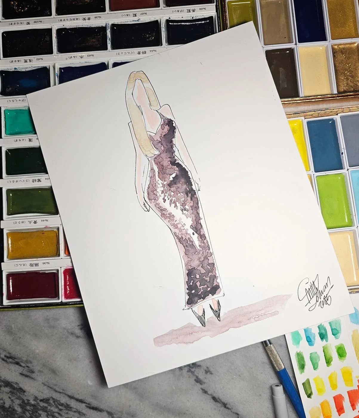 Close up of a painting of a blonde woman in a sparkly dress laid on top of an assortment of watercolor pans.