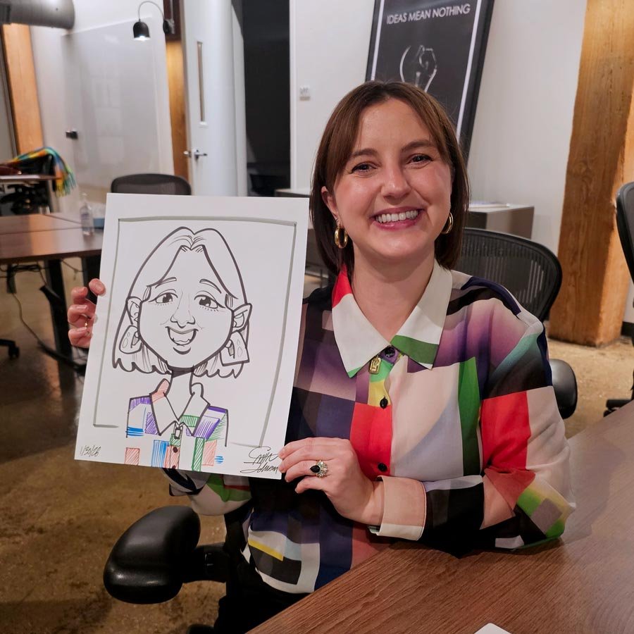 A woman with a colorful patterned shirt holds up her caricature.