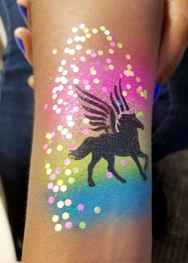 Tattoo of black pegasus with a rainbow gradient background and glitter surrounding the design.