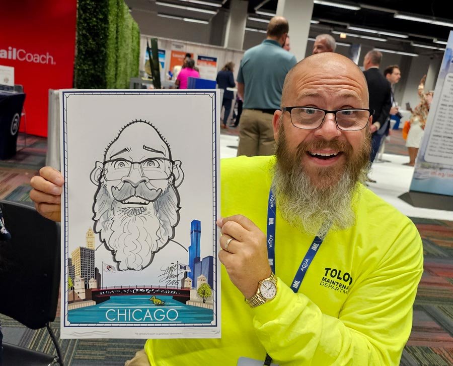 A bearded man in a bright yellow shirt smiles as he holds his caricature with a Chicago river border.