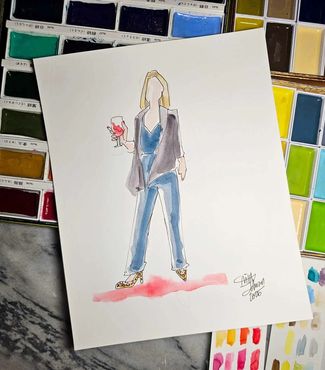 Close up of a painting of a blonde woman in a dark outfit and cheetah-print heels with a glass of wine laid on top of an assortment of watercolor pans.