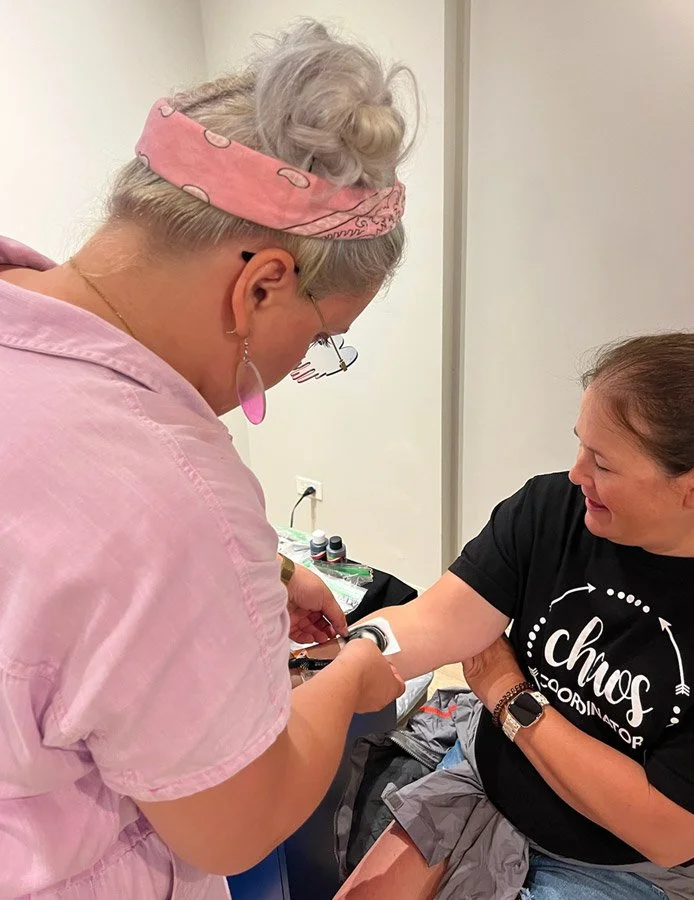 Artist attaches sticky stencil to client for their temporary tattoo.