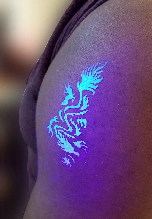 Tattoo of a dragon glowing under a blacklight.