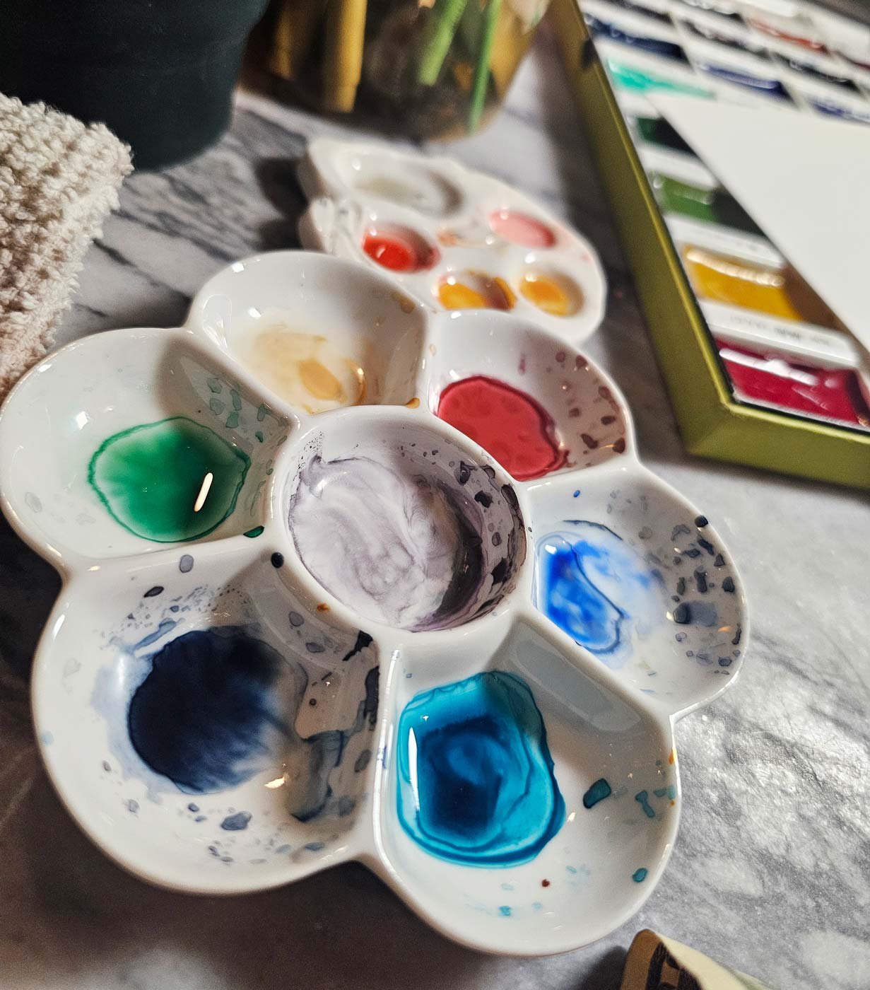 Close up of a porcelain watercolor dish with multiple mixed watercolors.