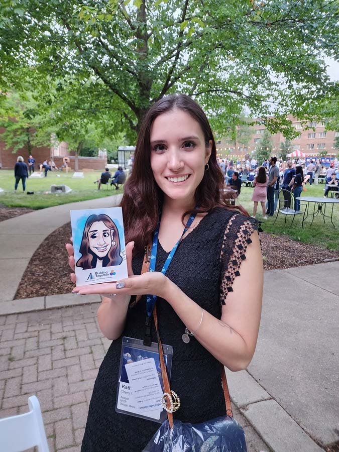 A smiling woman is holding her 4x6 digital caricature print.