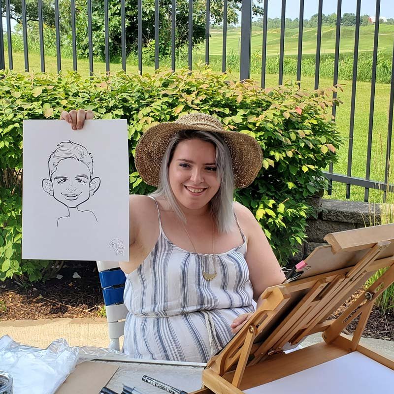 Artist holds a caricature at a pool party.
