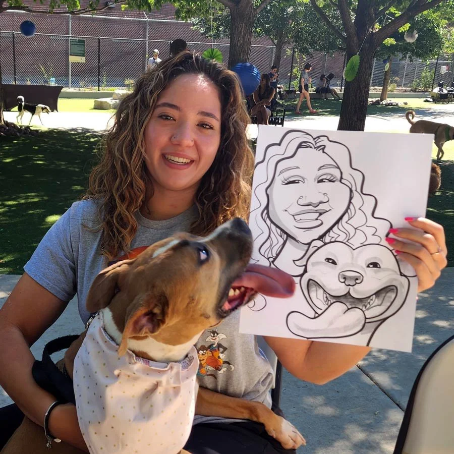 A woman is holding up her caricature and her dog while the dog attempts to lick her.