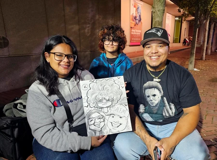 A family of 3 is laughing while holding their caricature.