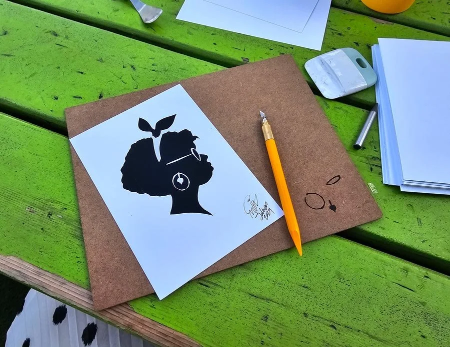 Silhouette of woman with glasses and a bow in top of a brown cutting board and a green table.
