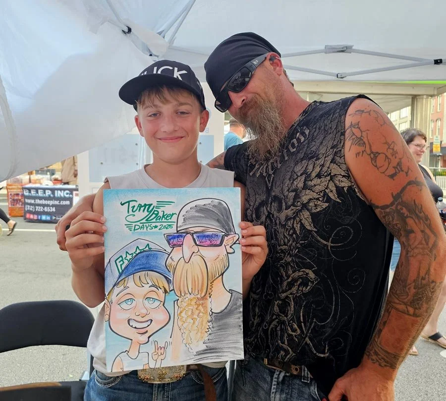 A smiling boy and his bearded father pose with their color caricature at a festival.