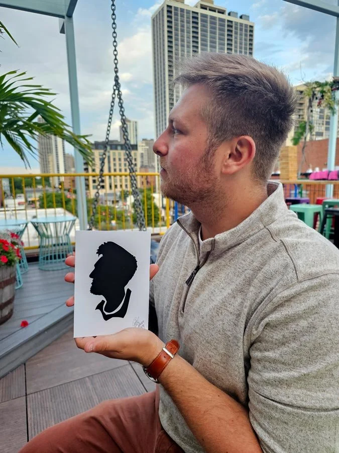 A man at a rooftop bar holds up his silhouette.
