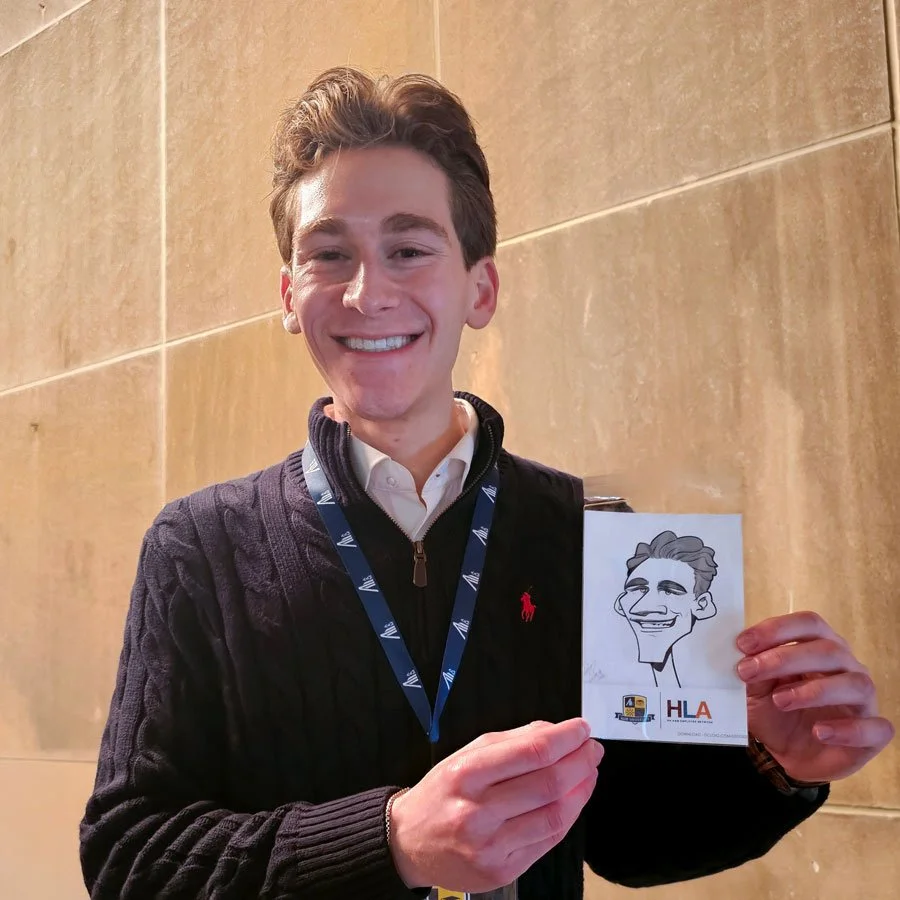 A young man holds up his 4x6 digital caricature print at an intern event.