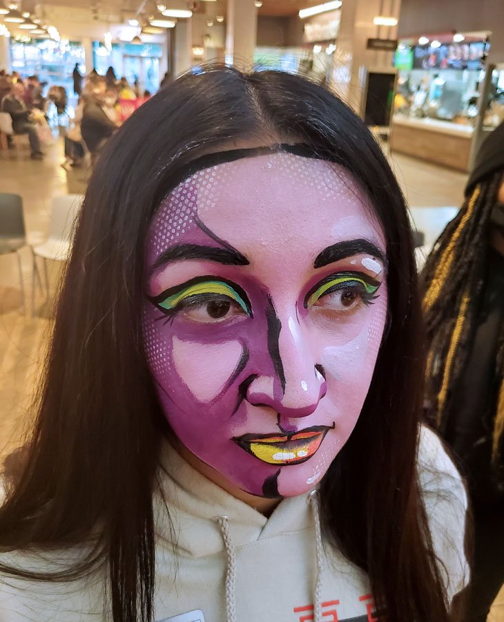 A woman is wearing a pop-art style face paint.
