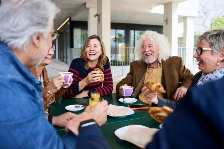 Retirees laughing and enjoying breakfast together around a table