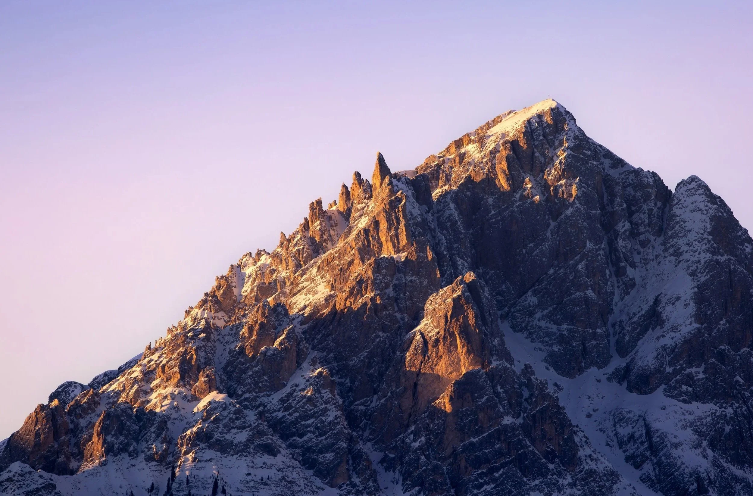 Snow-capped mountain peaks during sunset with a clear sky.