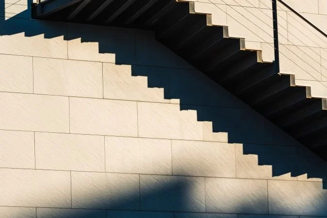 Abstract architectural staircase with repeating angular steps, representing the layered structure of Medicare's parts and deadlines