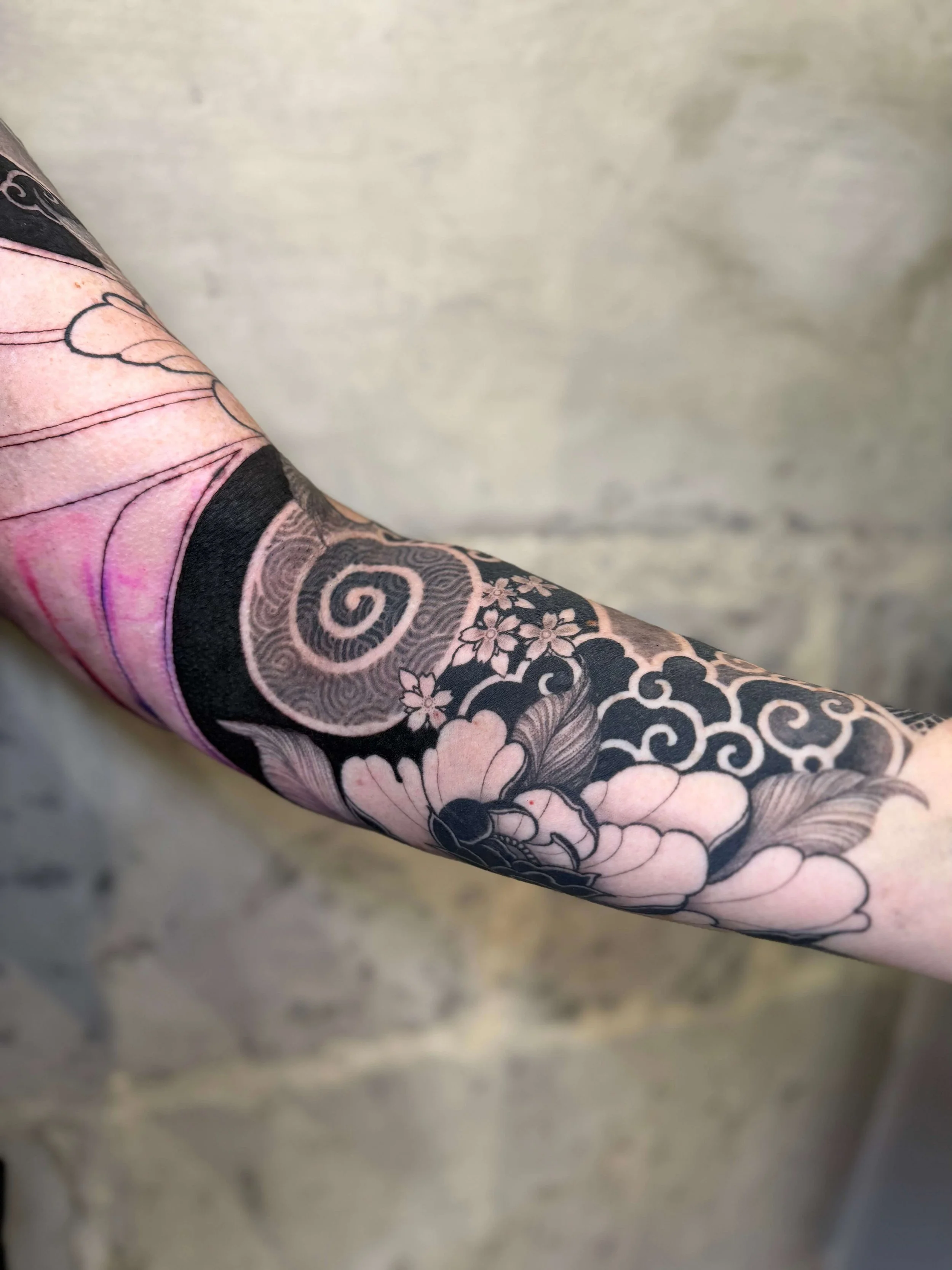 Tattoo sleeve featuring floral and traditional Japanese motifs on a person's arm.