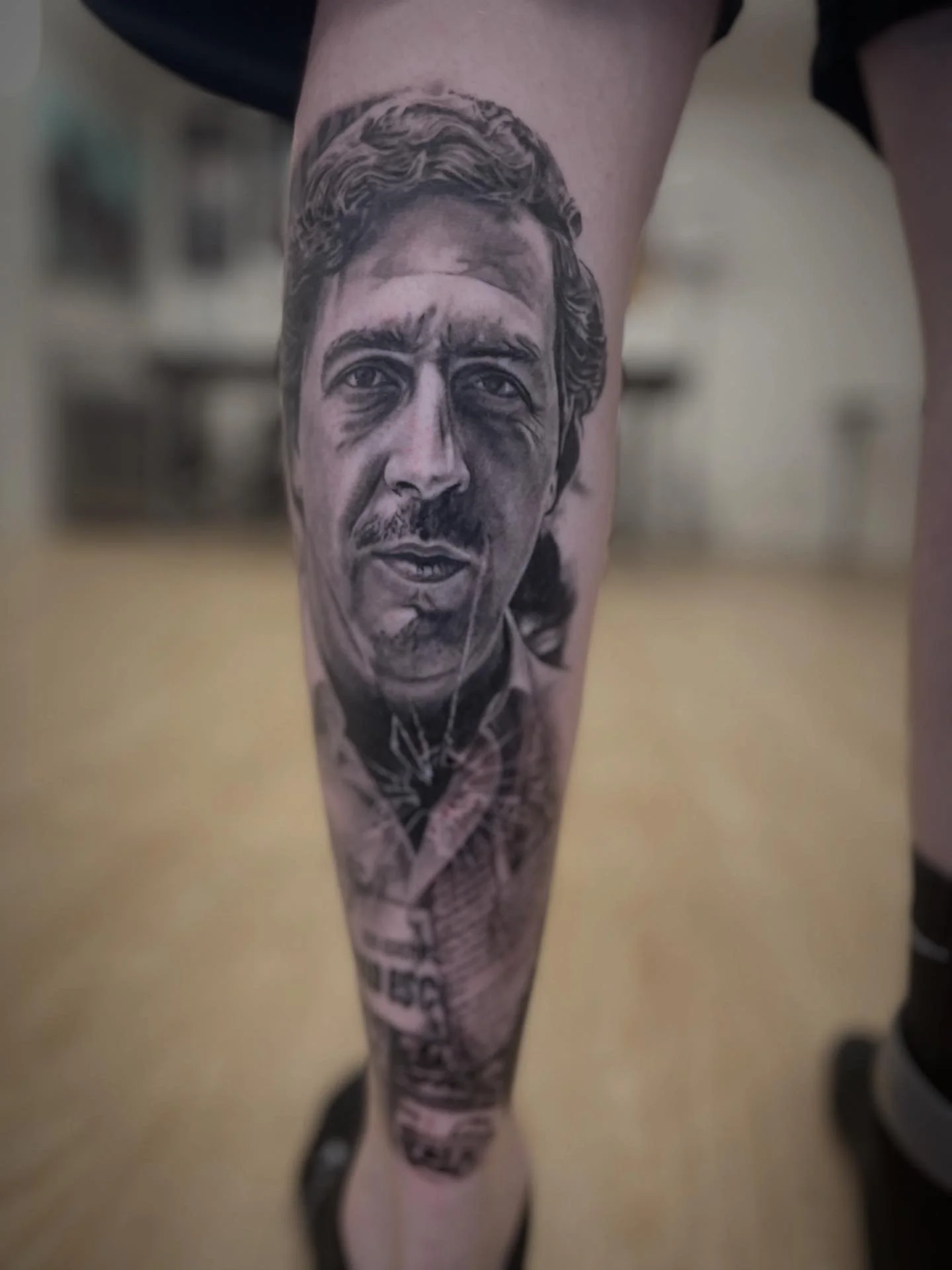 Close-up of a human leg with a detailed black and gray tattoo of a man's face and upper body.