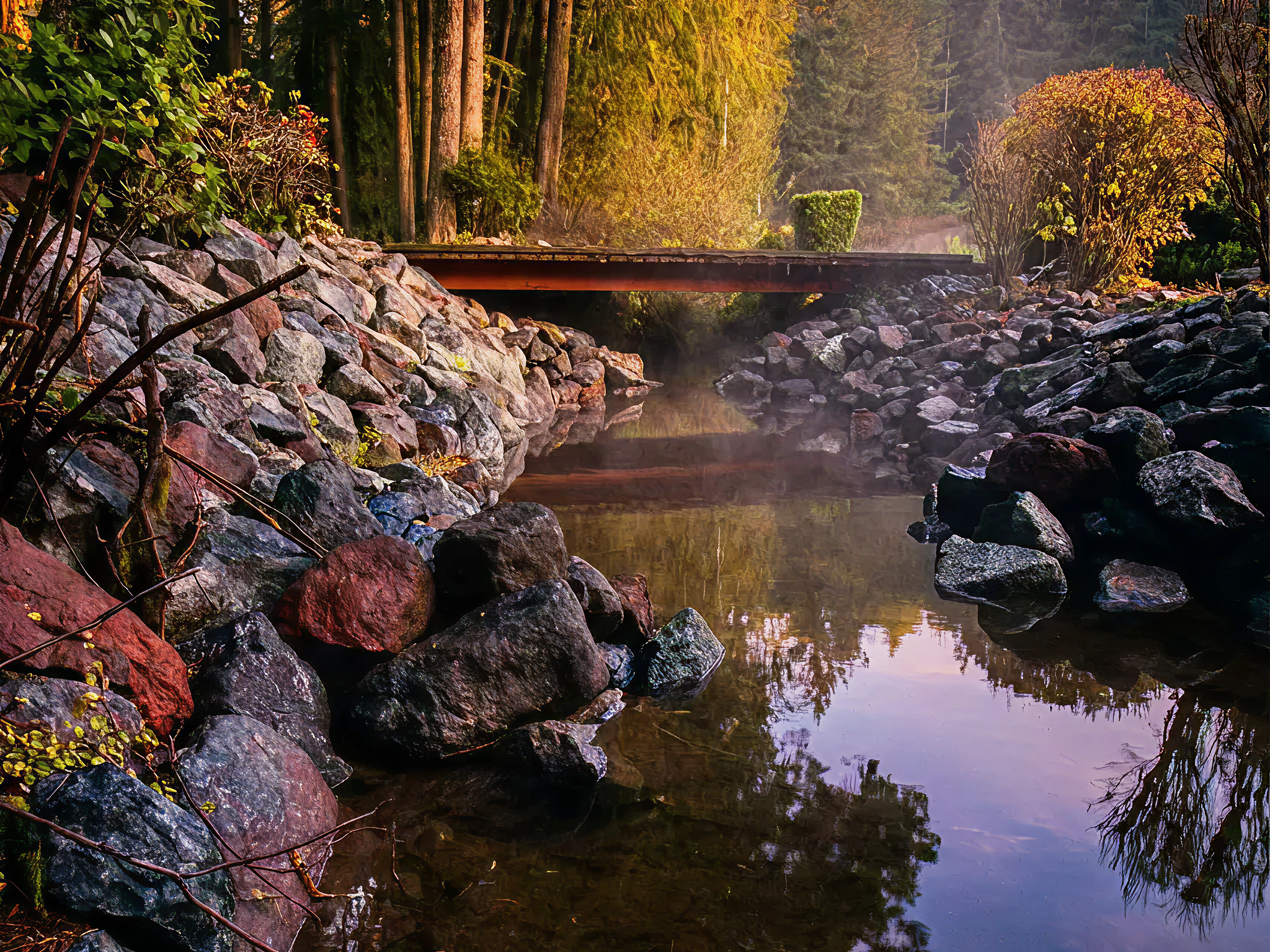 Drainage solutions in Coos Bay, Oregon with rocks on both sides, a wooden bridge overhead, and trees with autumn leaves in the background.