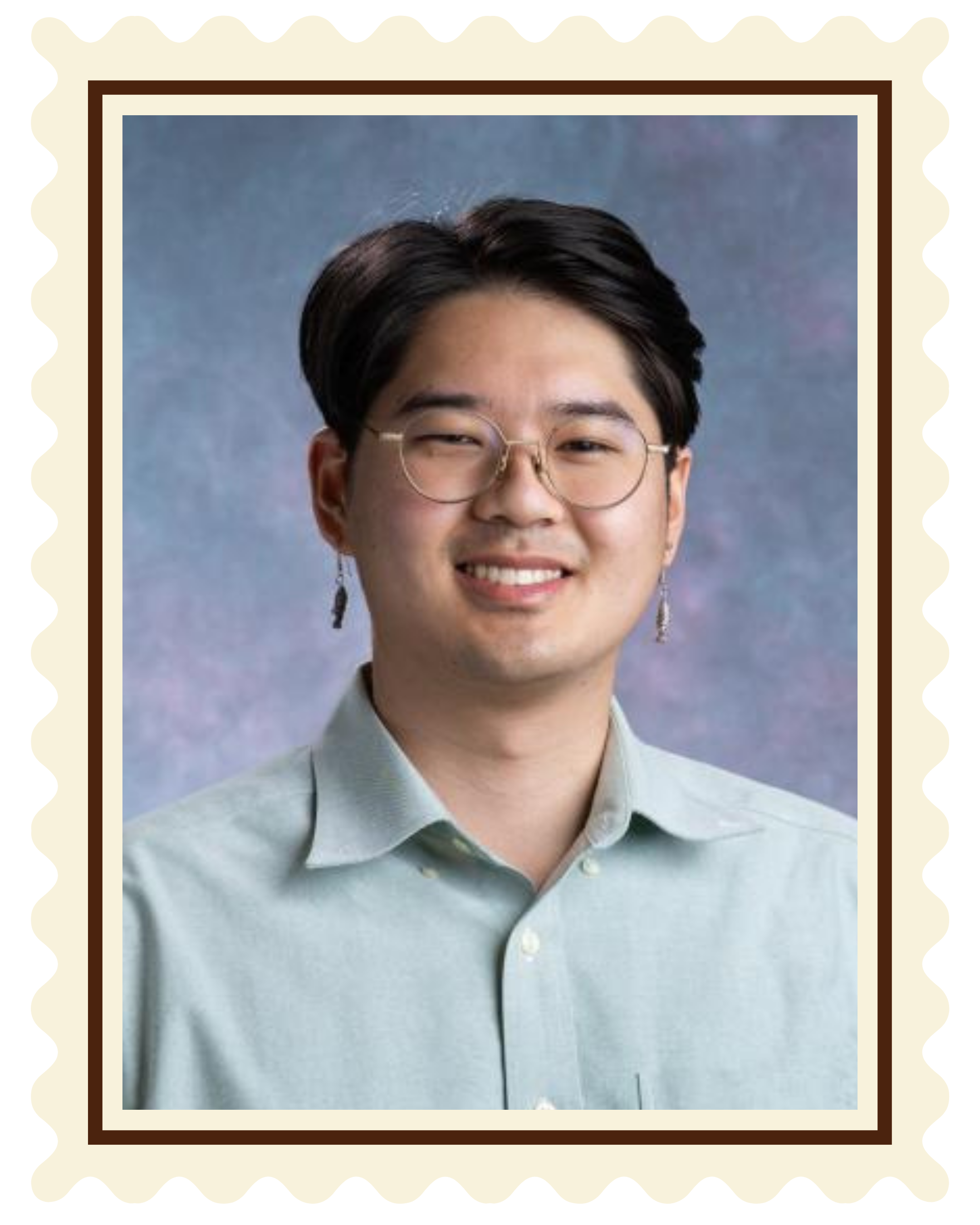 A young man with glasses, dark hair, light skin, smiling, wearing a light green button-up shirt, and earrings, against a blue and purple background.