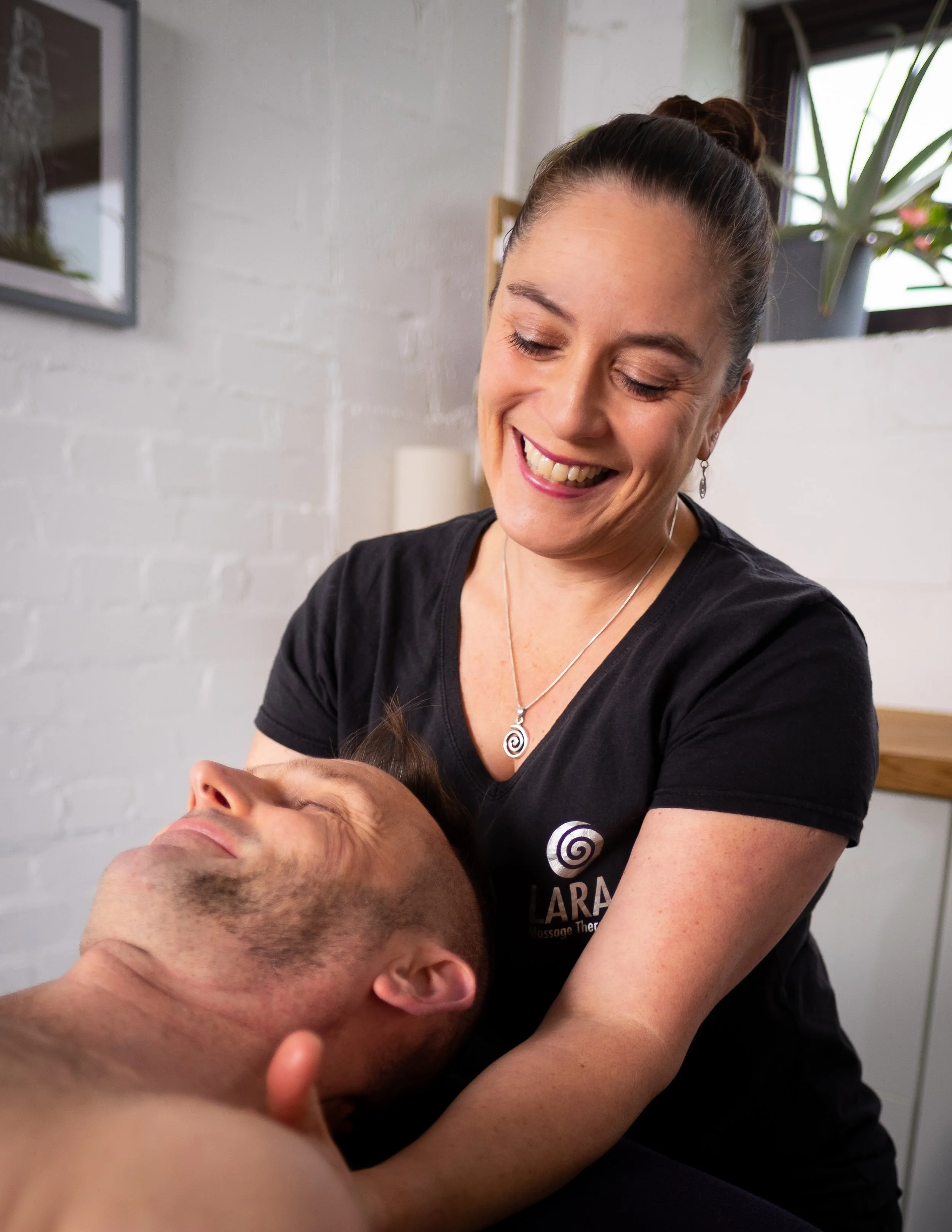 A massage therapist treating a mans neck
