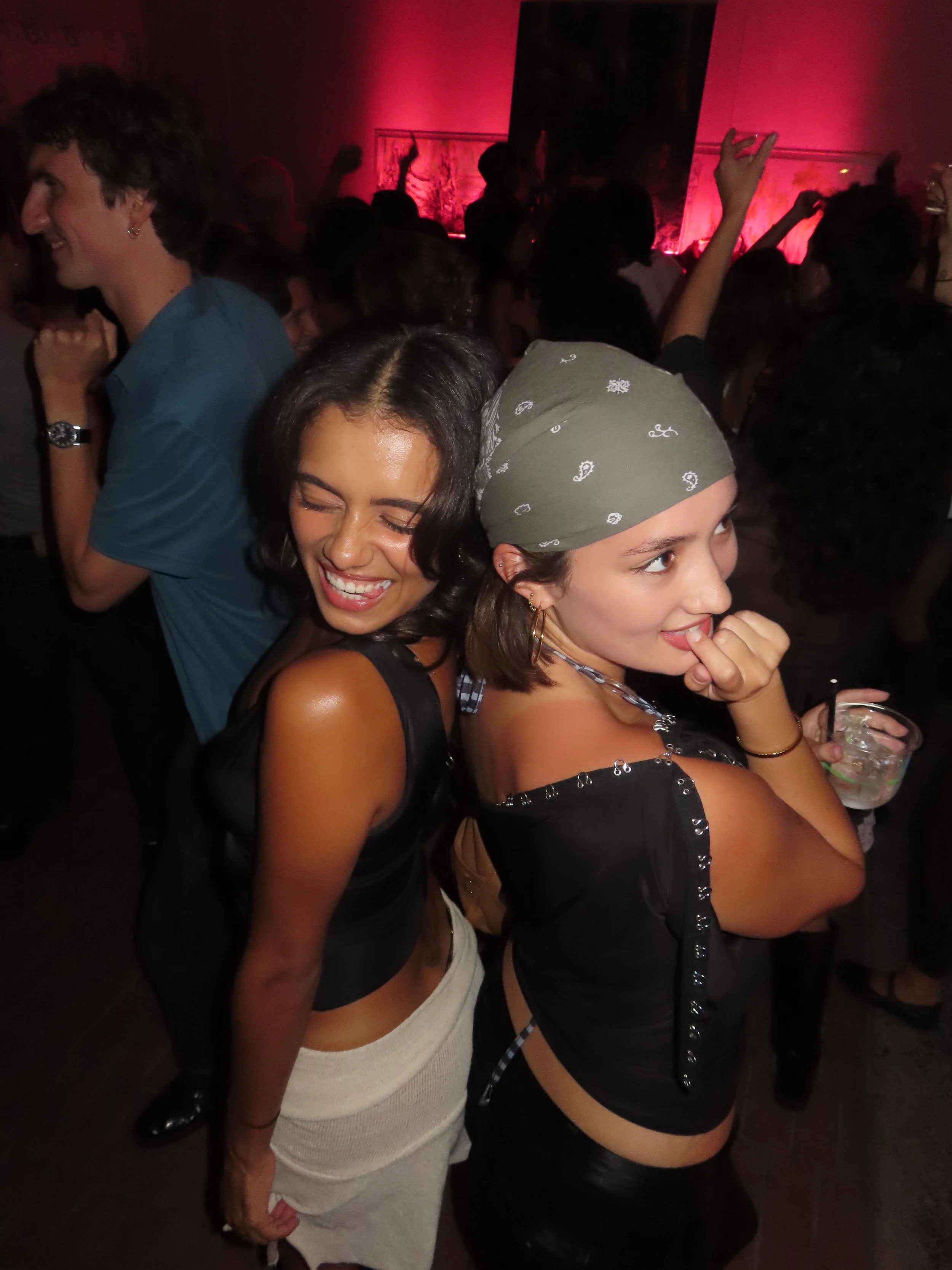 People dancing and enjoying themselves at a party or nightclub with red lighting.